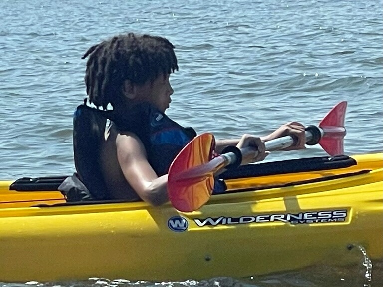 Tre'shawn paddles a kayak in lake at Salisbury Summer Kids Camp.