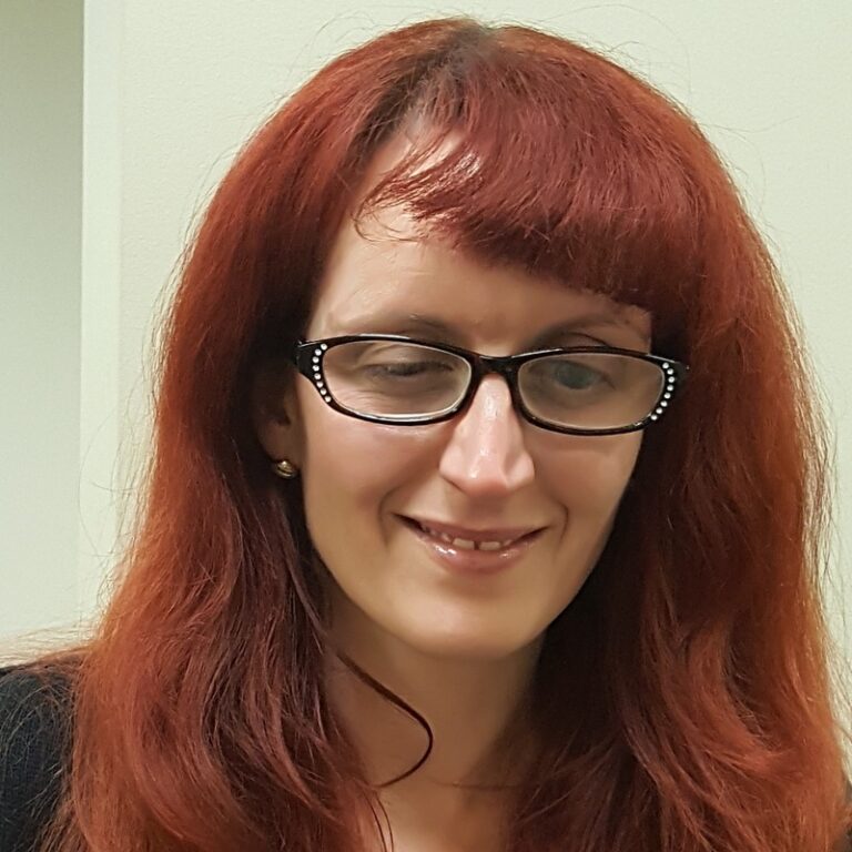 With lovely red hair and stylish glasses, Laura Shroyer smiles beautifully into the camera.