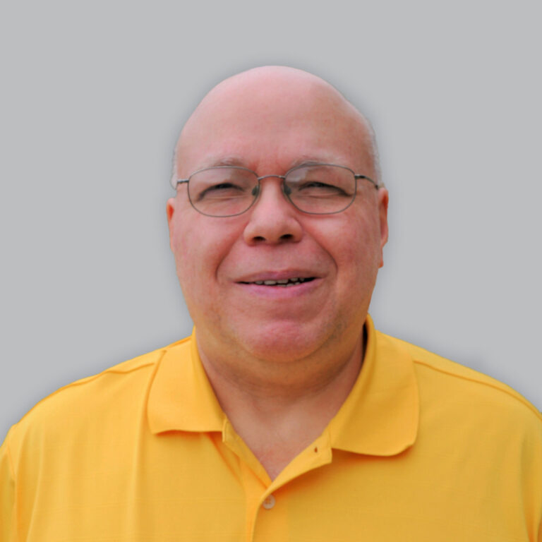 Photo shows a headshot of Mark wearing a yellow collar shirt and smiling at the camera.