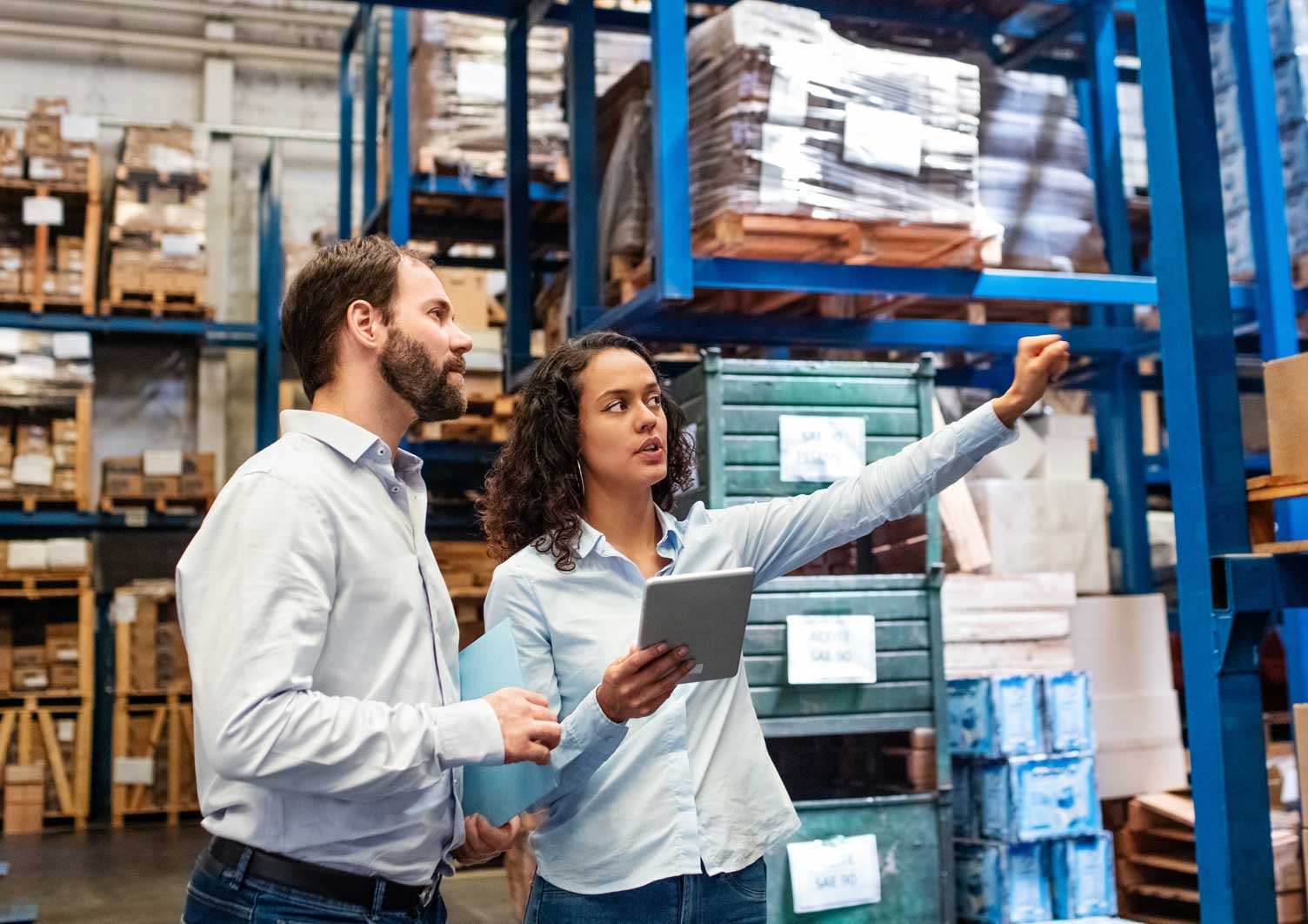 Two workers in warehouse checking stock on shelves.