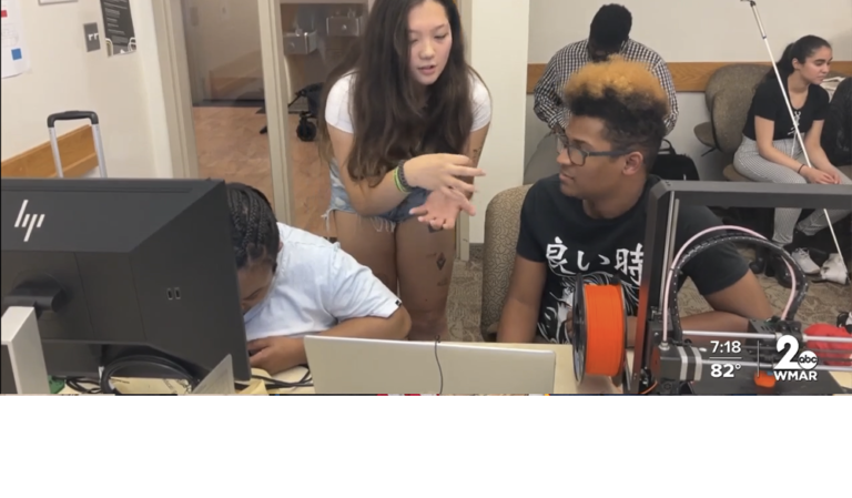 Harford Community College student helps two blind campers 3D print personalized luggage tags in computer lab equipped with 3D printers and computers with printing software. More campters wait their turn.