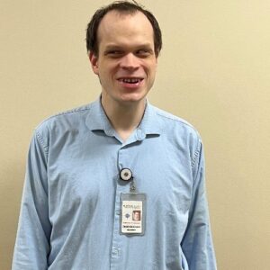 Jake Schmude, Solutions Architect at BISM, wearing a blue button-down shirt and smiling