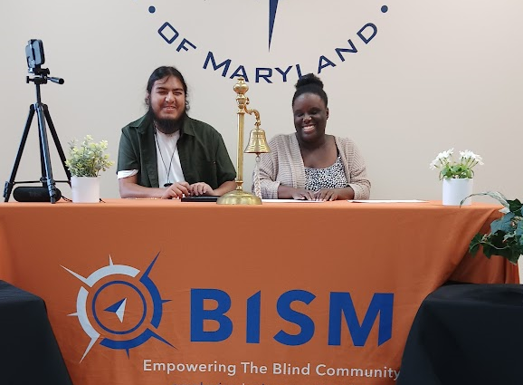 Alicia Crosson, on right wearing a proud smile, reads braille. She is accompanied at the awards table by Antonio Menedez, her mentor and instructor.