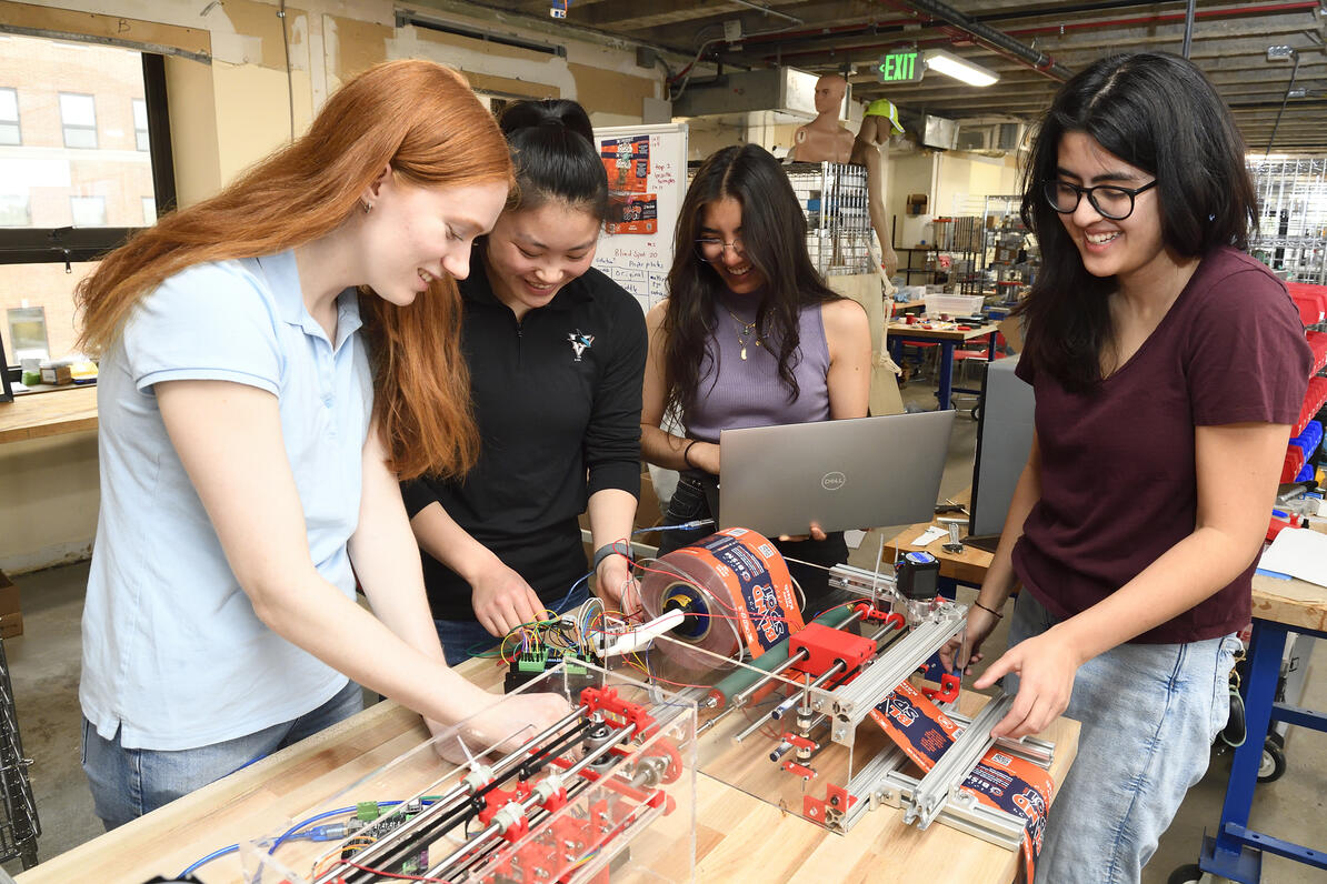Four Johns Hopkins engineering students demonstrate printer they designed to print braille beer labels. Photo by Will Kirk / Johns Hopkins University.