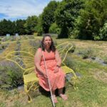 Danielle Earl sitting in a garden on a butterfly bench.