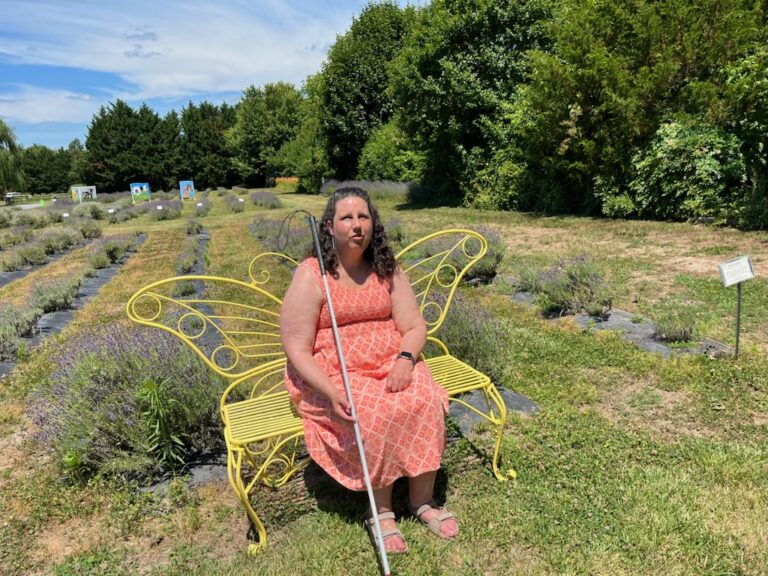 Danielle Earl sitting in a garden on a butterfly bench.