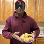 BISM SAIL student wearing sleep shades holds up his finished biscuits in front of him.