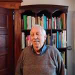 Alfred smiling and standing in front of a book shelf.