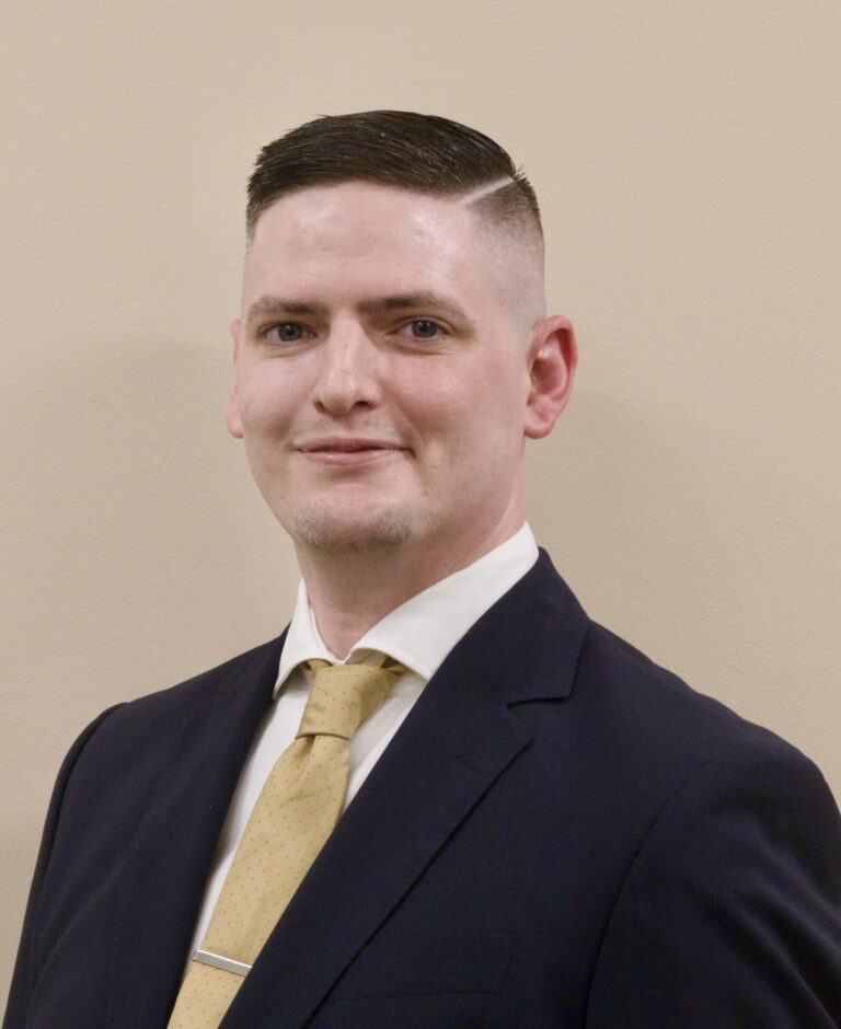 Dan's headshot. He is turned slightly towards the camera, looking straight at it and smiling.