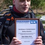Dmitrii holding up a plaque from disabled divers international that is a certificate of acheivement.