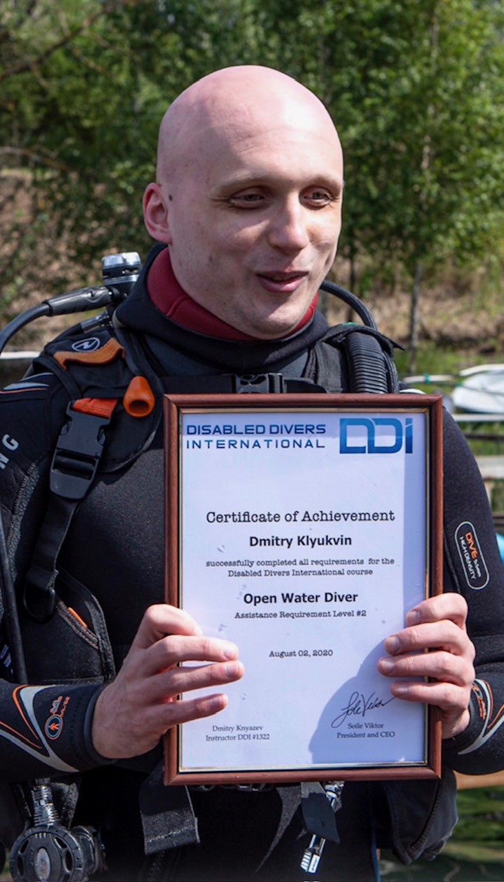Dmitrii holding up a plaque from disabled divers international that is a certificate of acheivement.